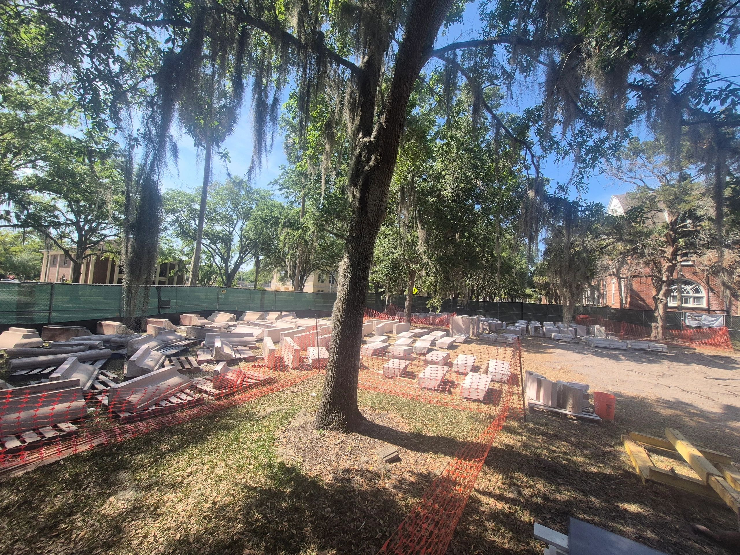 Construction materials under tree with orange fencing.