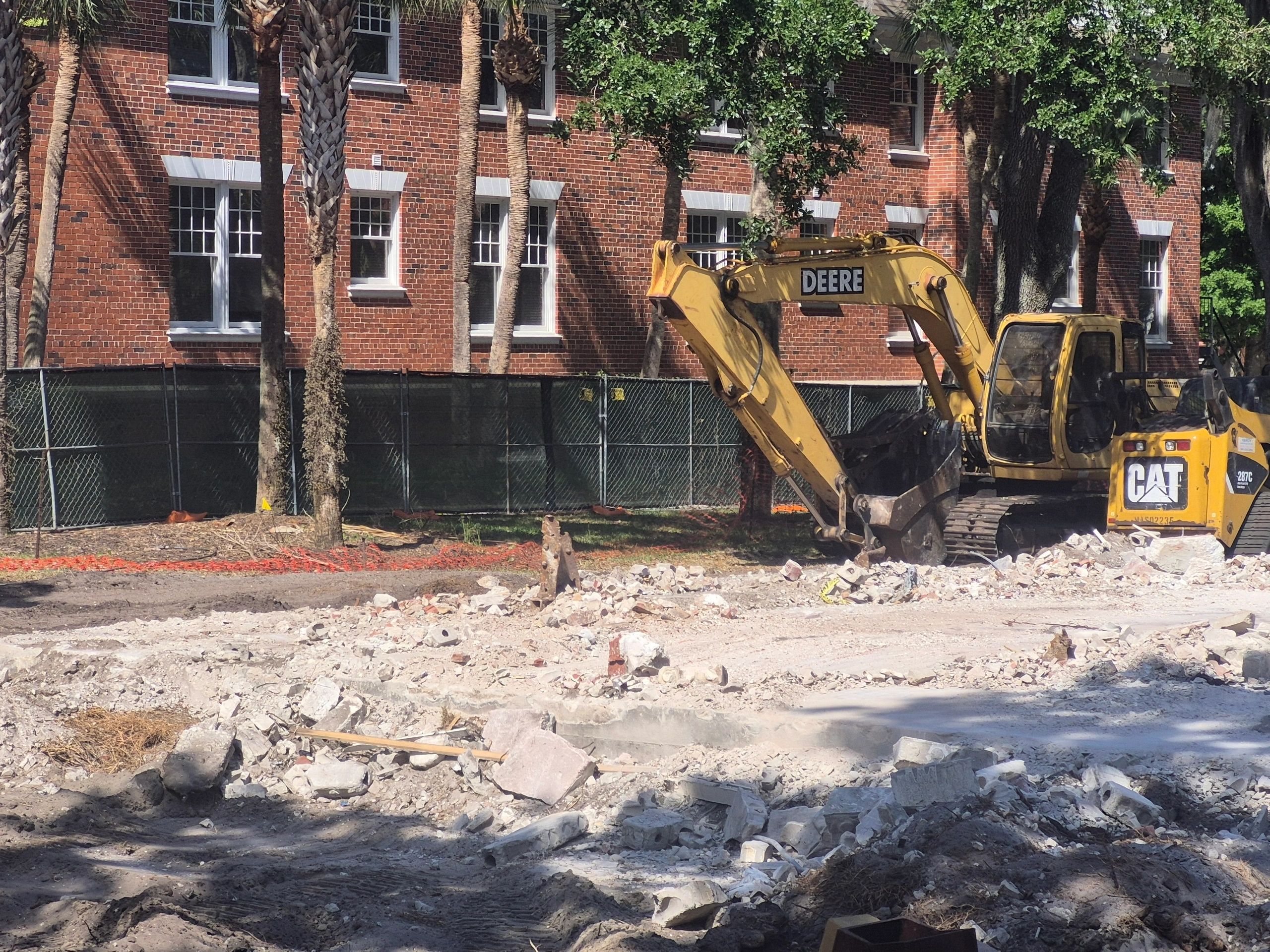 Excavator clearing debris at urban site.