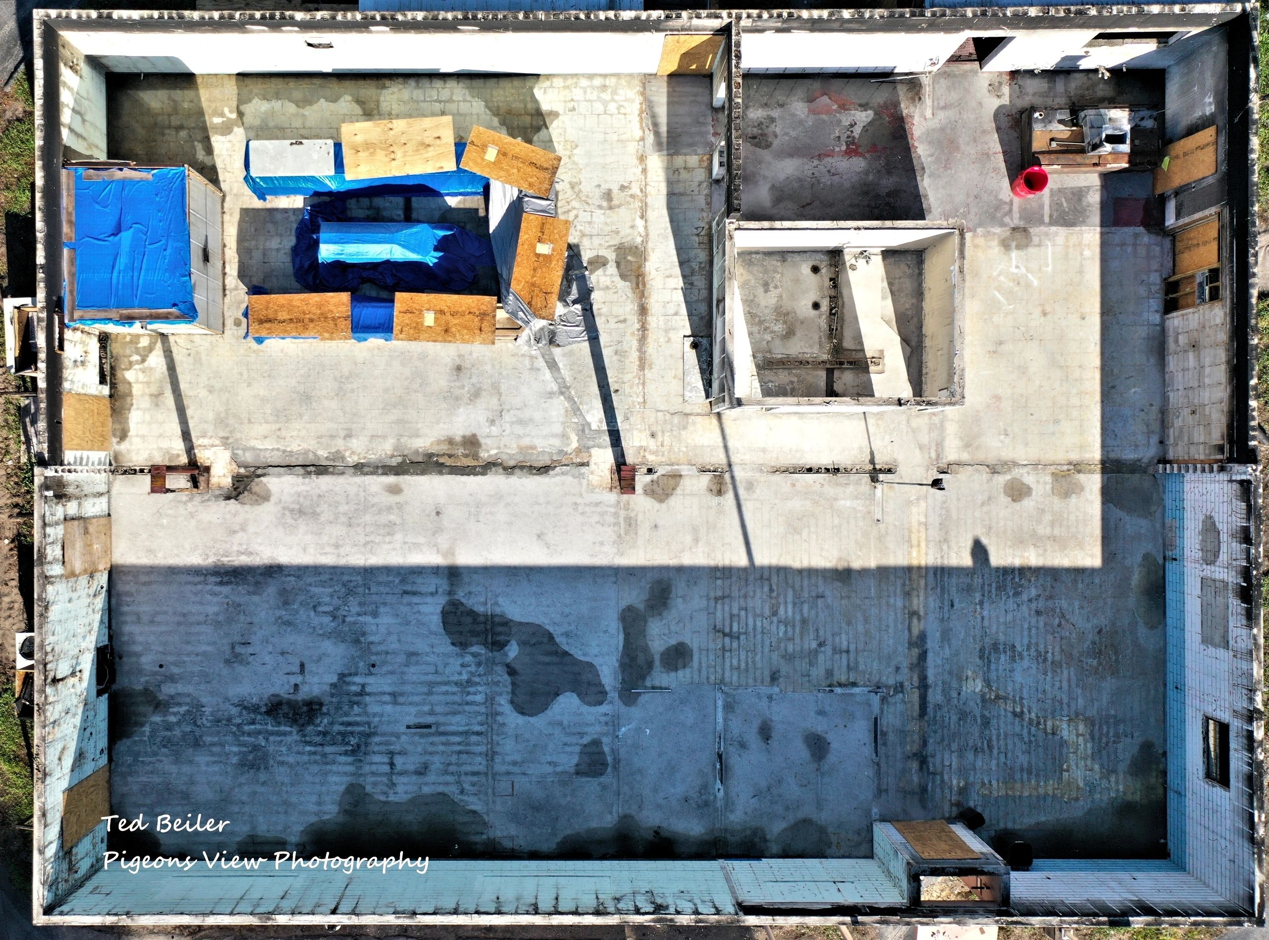 Construction site with blue tarps and shadows.