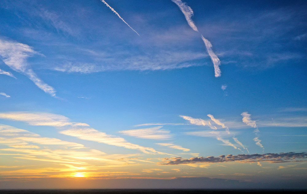 Contrails streaking across a vibrant sunset