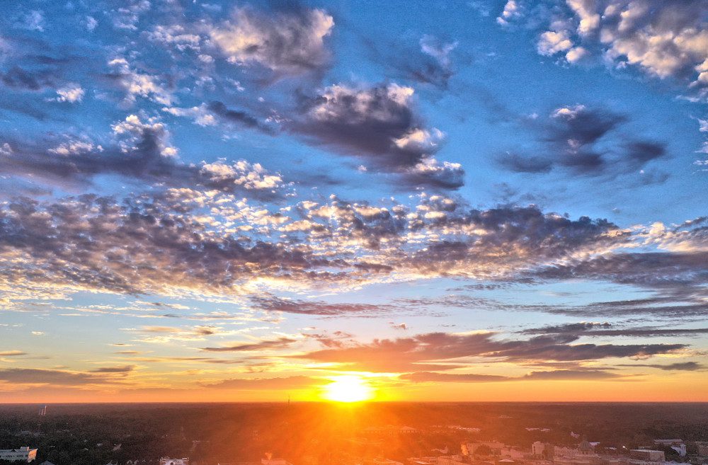 Sunrise with vibrant clouds over city skyline.