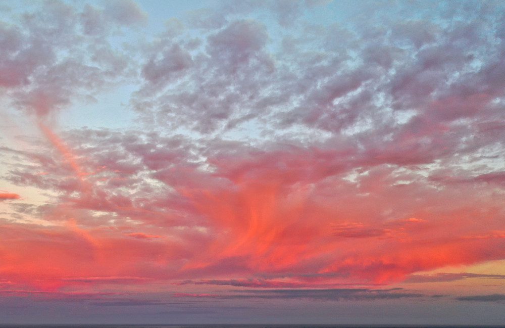 Vibrant pink sunset with scattered clouds.