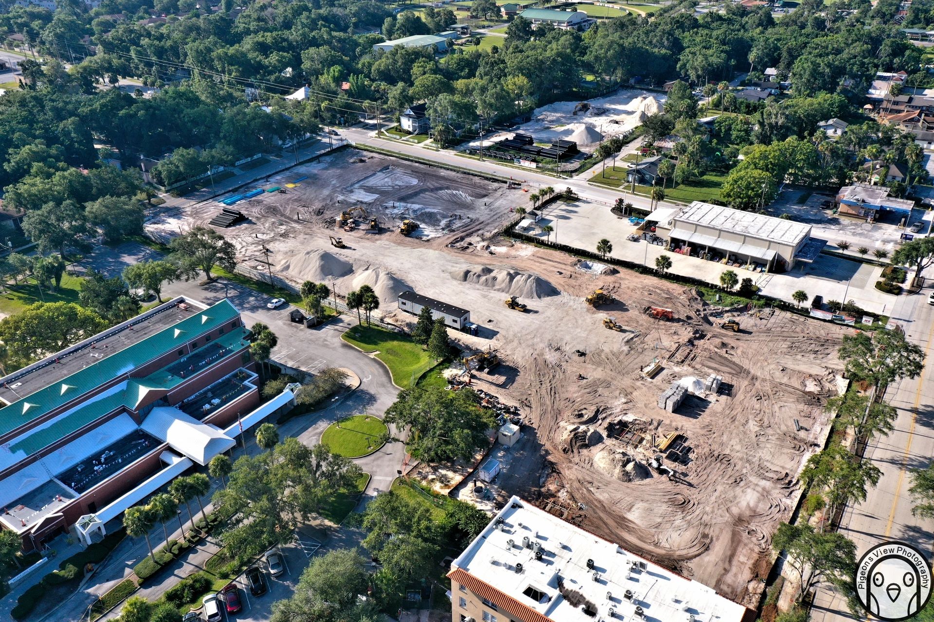 Construction site aerial view with surrounding buildings.