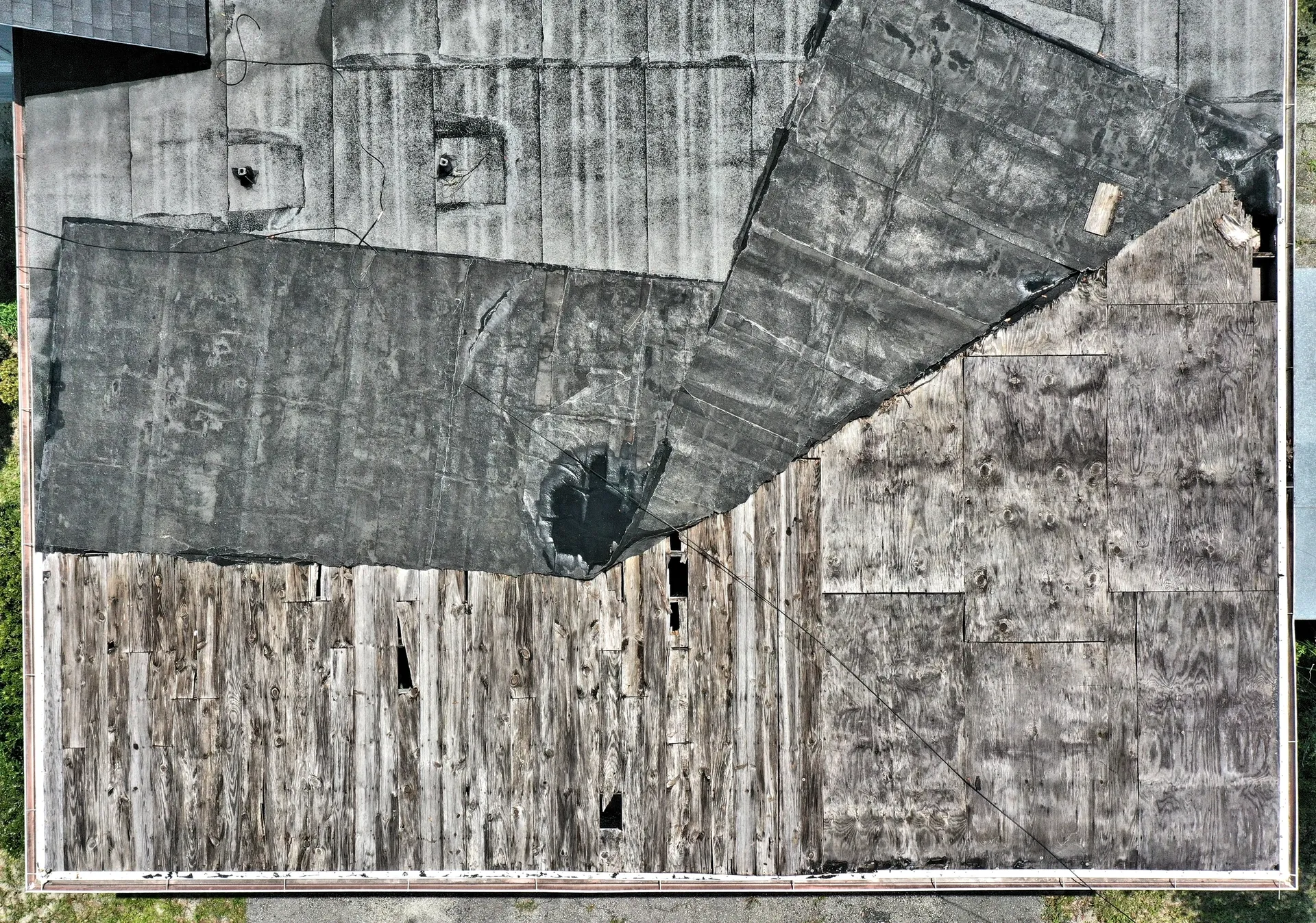 Damaged roof with missing shingles aerial view