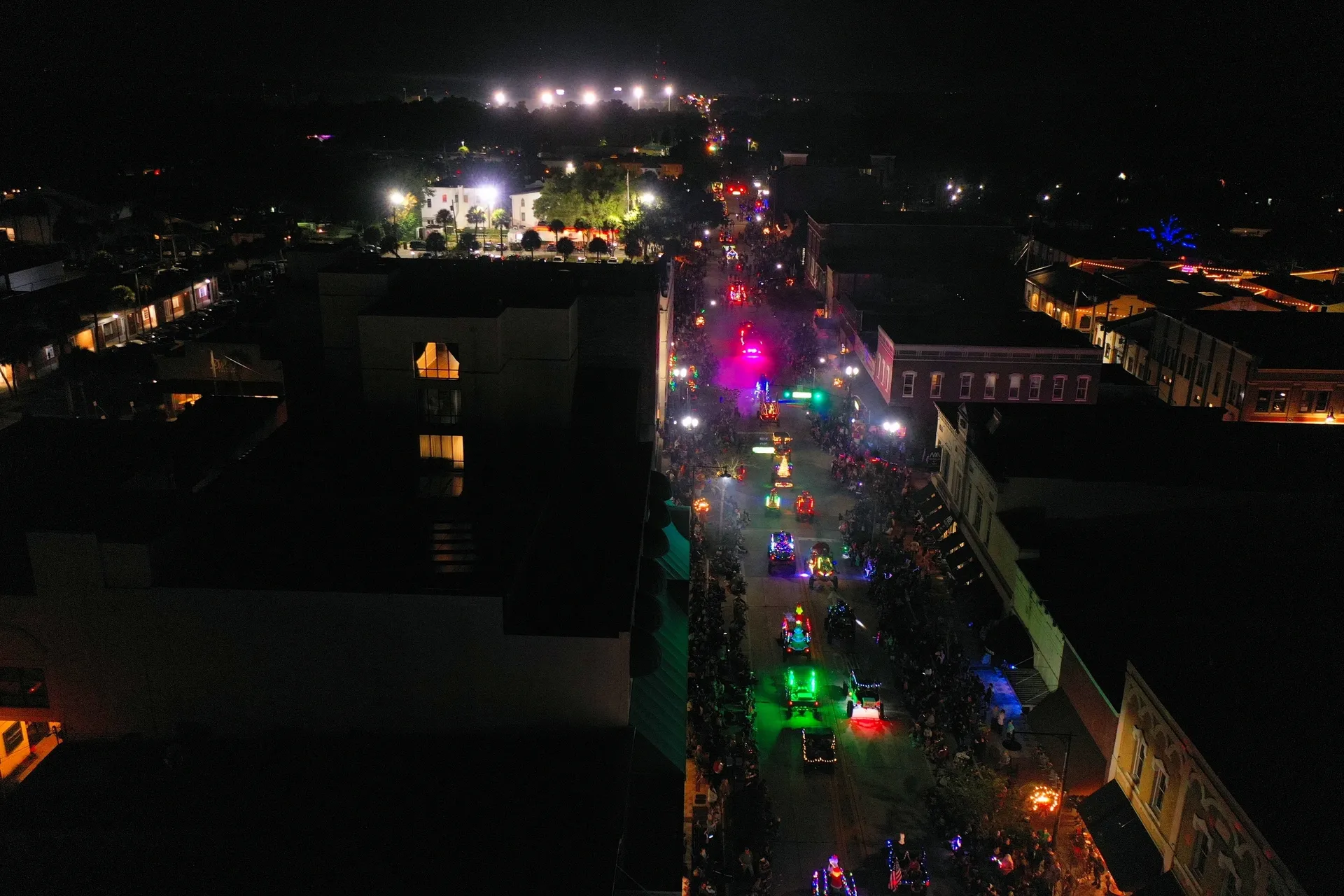 Vibrant lights along a nighttime street procession.