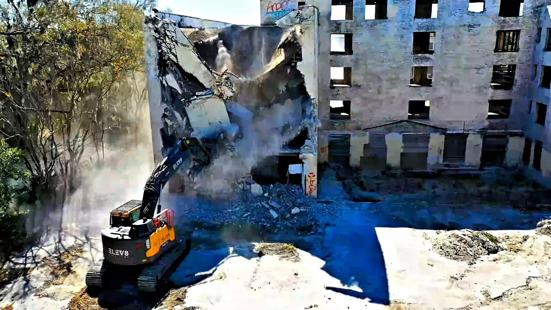 Excavator demolishing old building facade