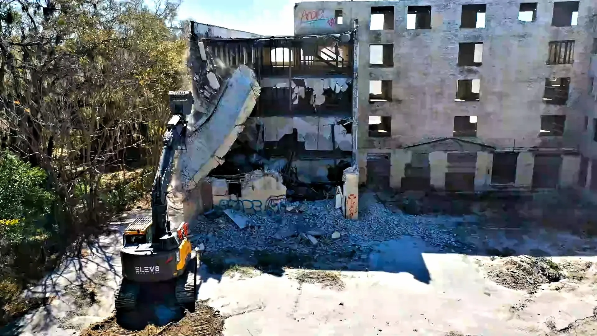 Machine tearing down abandoned building facade